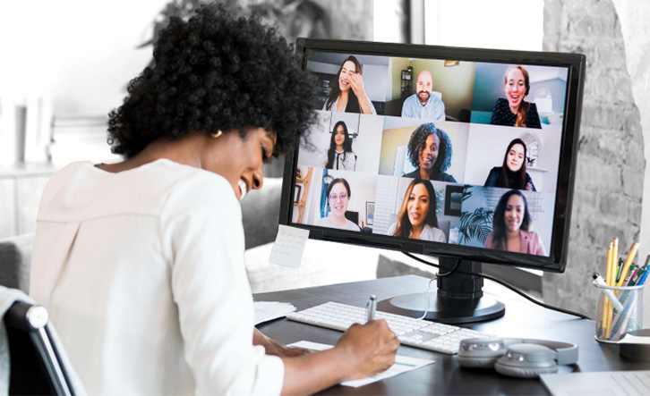 A lady noting on a paper while attending online meeting