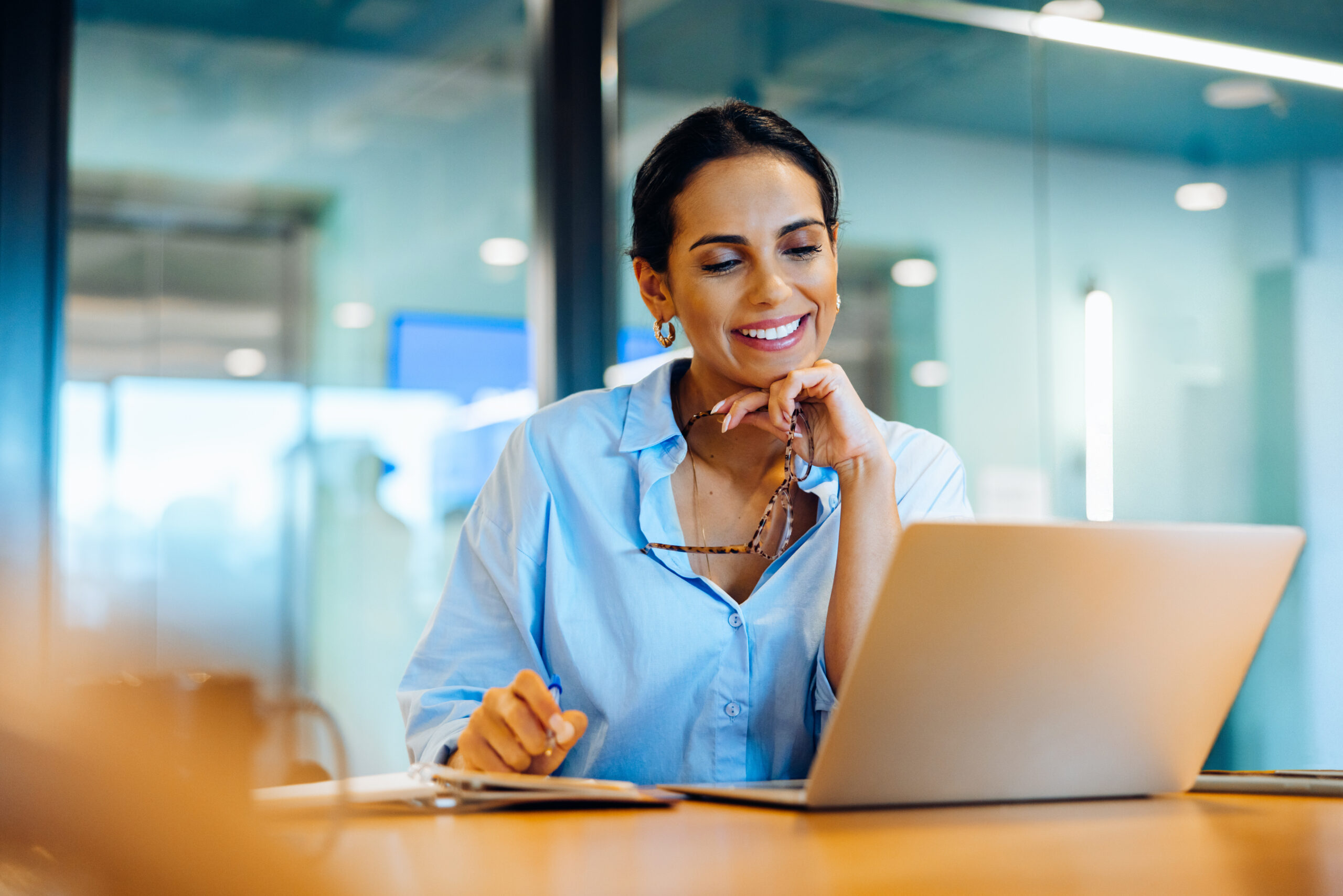A lady smiling at the laptop screen