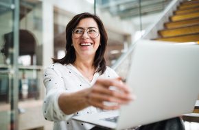 A lady holding laptop and smiling